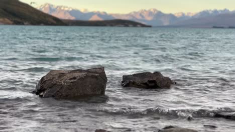 two large boulders in shallow waters of alpine glacier lake during golden hour