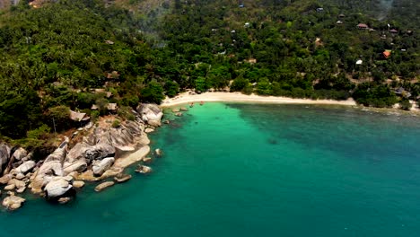 A-partial-overhead-orbit-that-moves-from-left-to-right,-showing-the-white-sandy-beach-and-crystal-blue-waters-of-Haad-Tian-resort-in-the-island-of-Koh-Tao-in-Surat-Thani-province,-Thailand