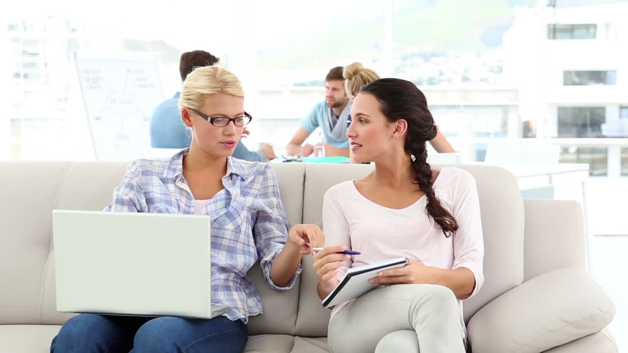 Partner creativi che condividono idee sul divano con i colleghi dietro