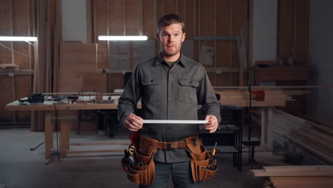 carpenter in workshop holding measuring tape