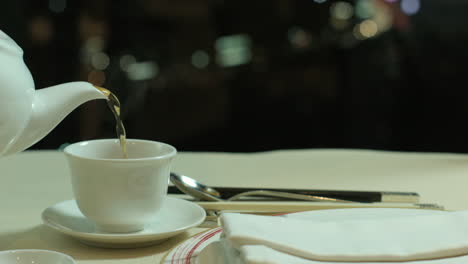 pouring hot tea on a cup in a rooftop restaurant