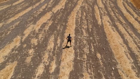 Persona-Corriendo-Por-Un-Campo-Marrón-árido-Desde-Una-Vista-Aérea-Con-Un-Dron