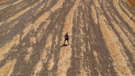 persona corriendo por un campo marrón árido desde una vista aérea con un dron