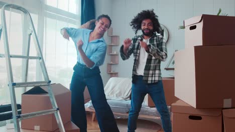 young happy woman and man dance rejoicing in buying new apartment or moving