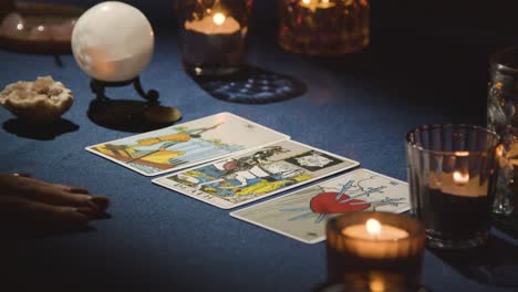 un primer plano de una mujer dando una lectura de tarot a la luz de las velas en la mesa 4