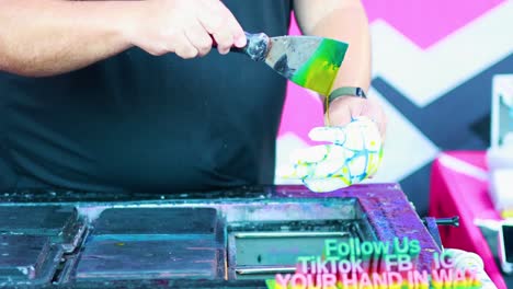 a person crafts a vibrant wax hand using a spatula, showcasing artistic technique and creativity in a lively setting