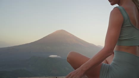 woman journaling thoughts and feelings in front of mount agung, sunrise