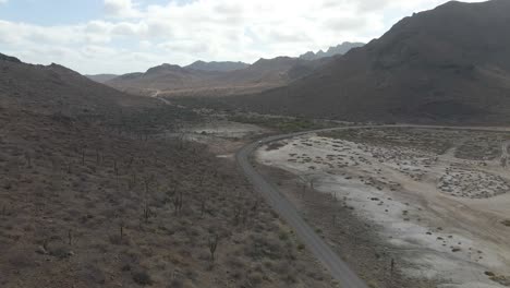 aerial: solo car driving on road through remote mexican desert, la paz, baja california sur