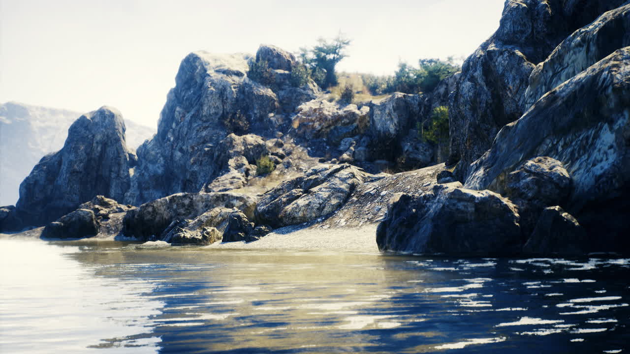 View of rocky coastline with calm waters and distant hills