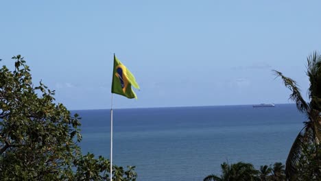 brazil flag close-up waving in the wind in 120fps slow motion with the vast ocean in the background in the historic city of olinda in pernambuco, brazil on a warm sunny clear summer day