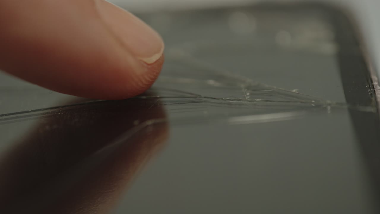 el dedo se mueve sobre el vidrio agrietado del teléfono inteligente