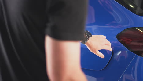 hombre cargando un coche eléctrico con cable usando una aplicación en el teléfono para monitorear el nivel de la batería