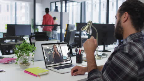 hombre del medio oriente hablando en videollamada con una colega de oficina en una computadora portátil en la oficina