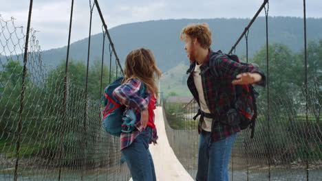 two hitchhikers enjoy jump on mountains river bridge. happy couple dance outdoor