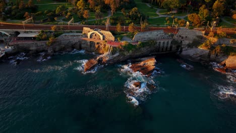 the mediterranean coastline in genoa at sunset, showcasing the rocky shore and greenery, aerial view