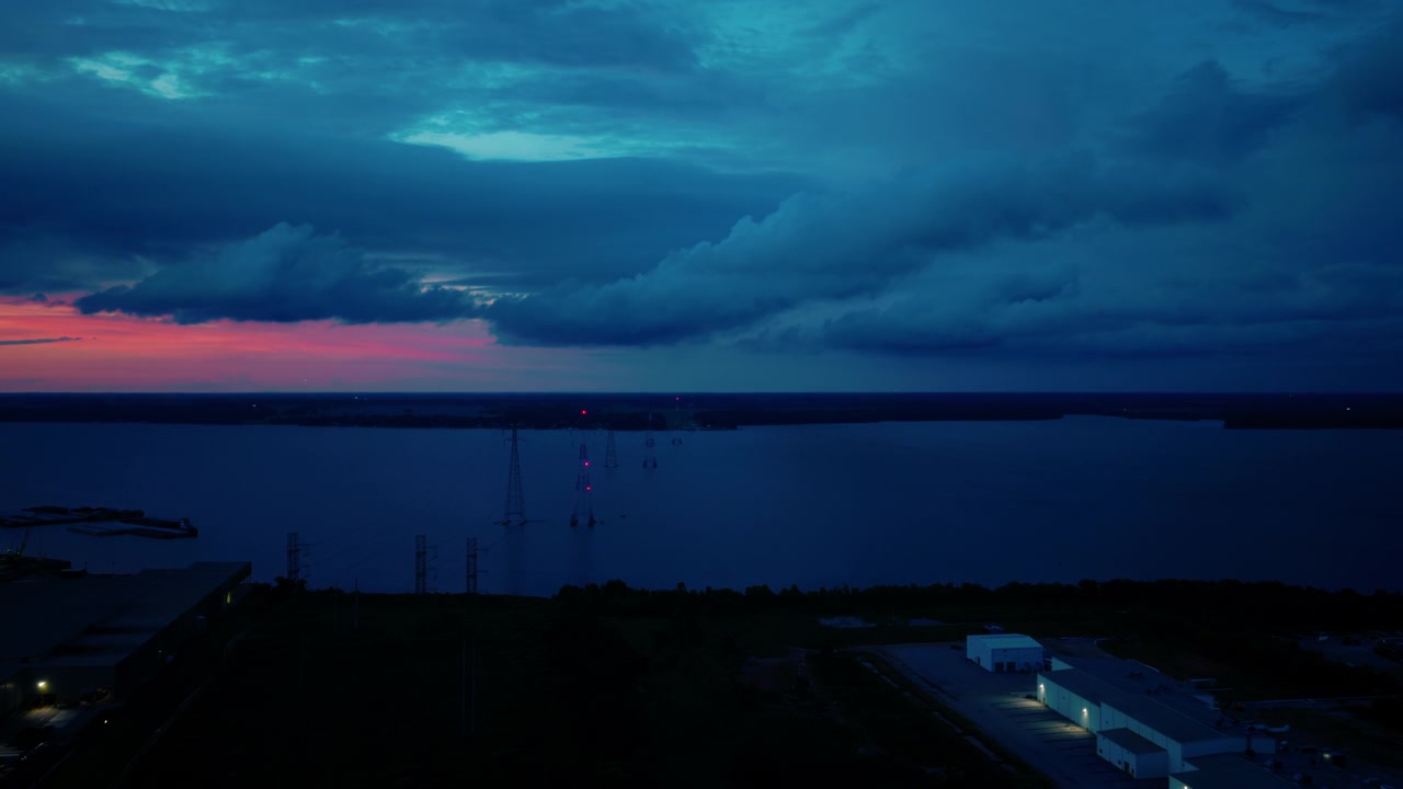 Aassive electrical transmission towers spanning the wide Tennessee River in Decatur, Alabama during a dramatic twilight sunset.