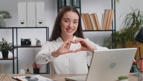 caucasian business woman makes symbol of love showing heart sign to camera express romantic feelings