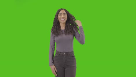 three quarter length studio portrait of woman against green screen smiling at camera 2