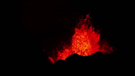 estallando lava caliente derretida del cráter del volcán brillando de naranja por la noche