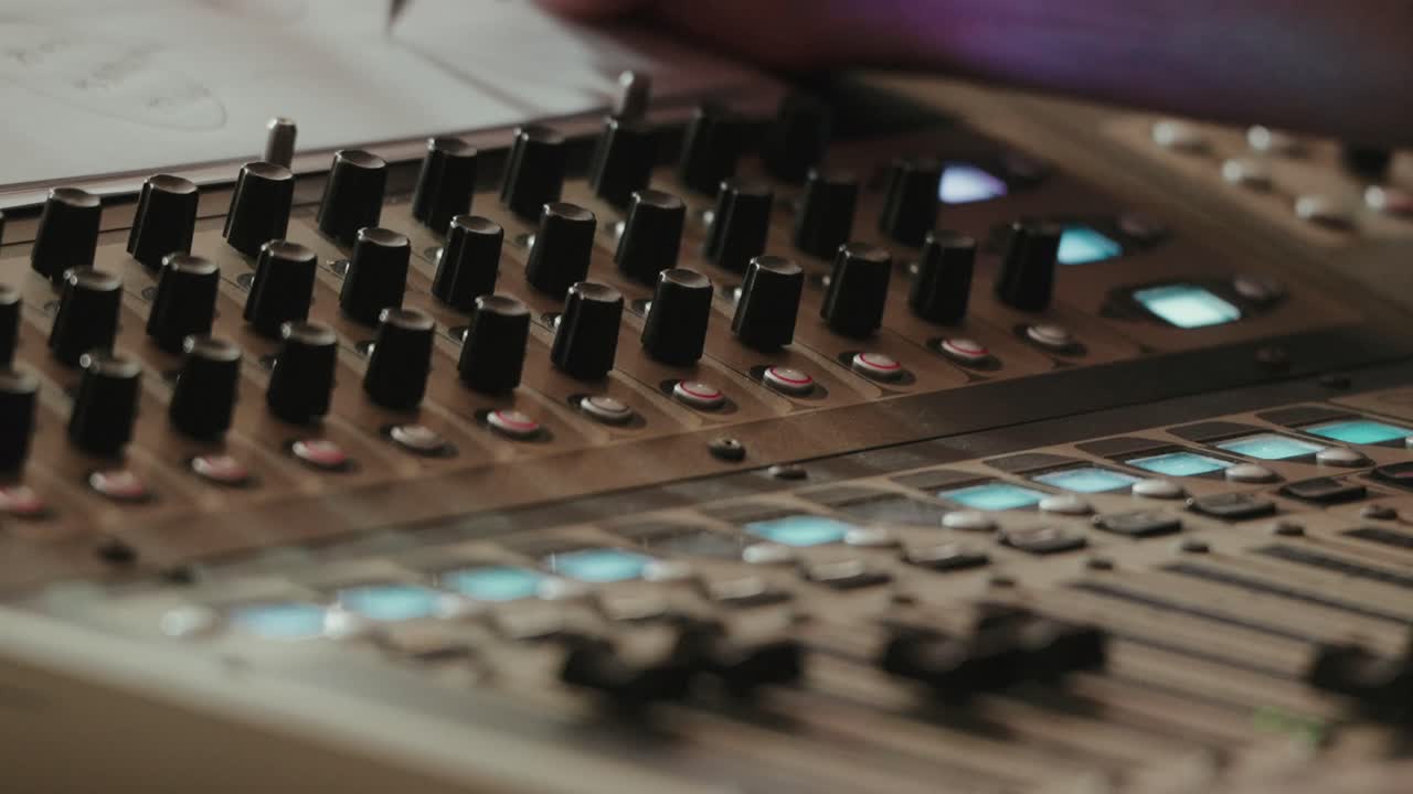 Close up of sound mixing desk with illuminated buttons and control knobs during live studio production