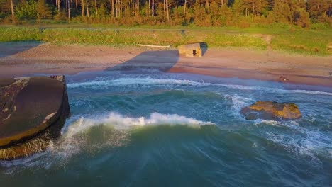 aerial view of abandoned seaside fortification buildings at karosta northern forts on the beach of baltic sea , waves splash, golden hour sunset, wide drone dolly shot moving left