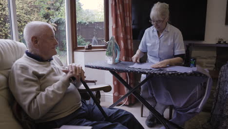 elderly man with caregiver ironing at home