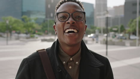 close up portrait of trendy young african american man wearing glasses laughing cheerful at camera enjoying urban lifestyle in city