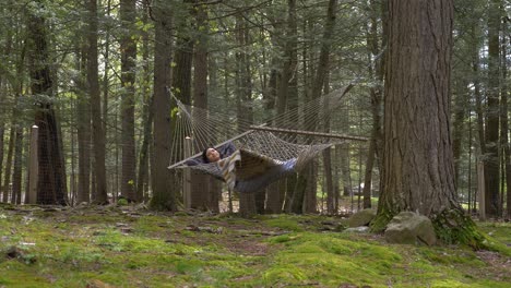 una mujer puertorriqueña despreocupada se balancea lentamente en una hamaca del bosque contemplando la vida.