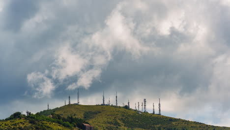 fast-moving clouds over hilltop covered with communication antennas and towers, stormy weather sky