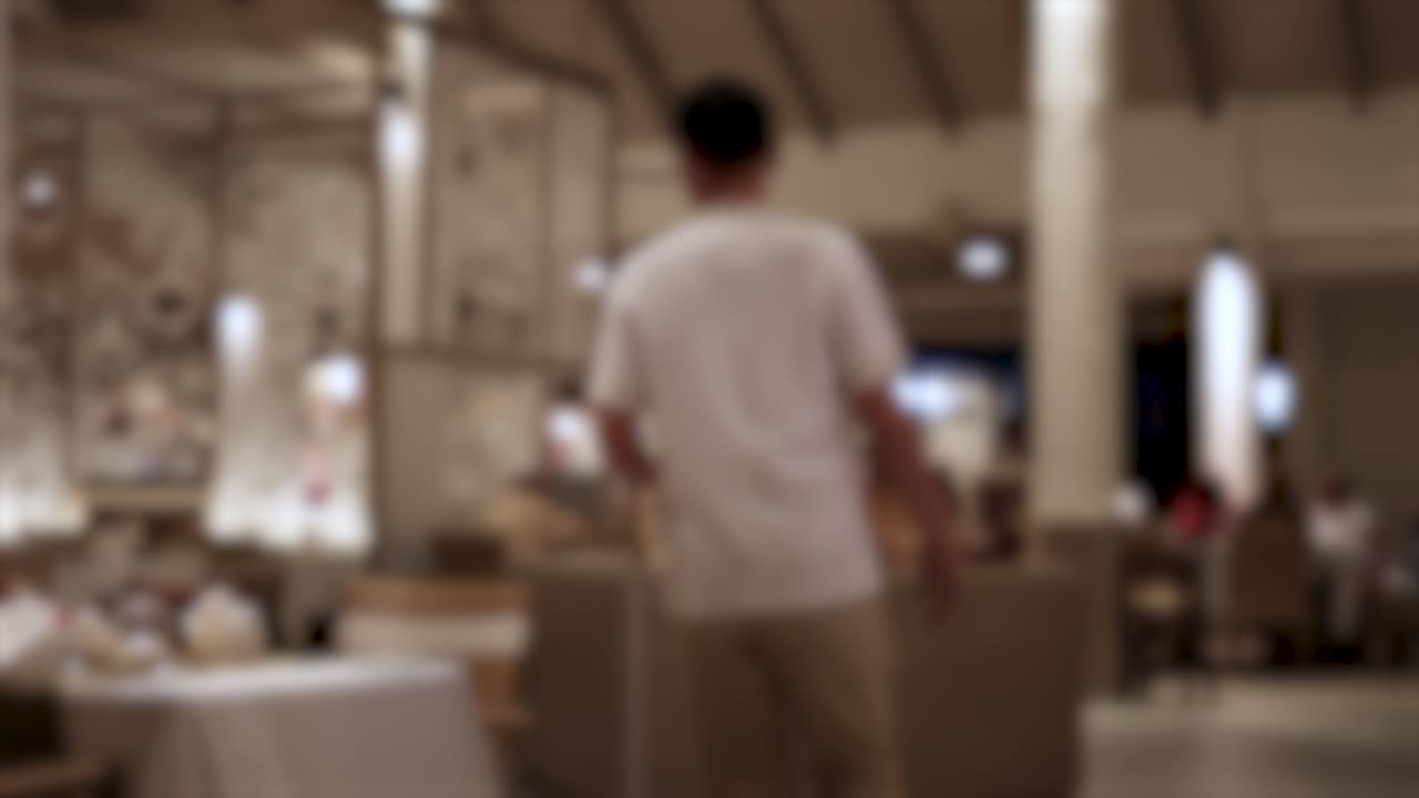 웨이터가 희미하게 조명된 우아한 레스토랑을 통과하여 차분하고 전문적인 태도로 테이블에 참석합니다.