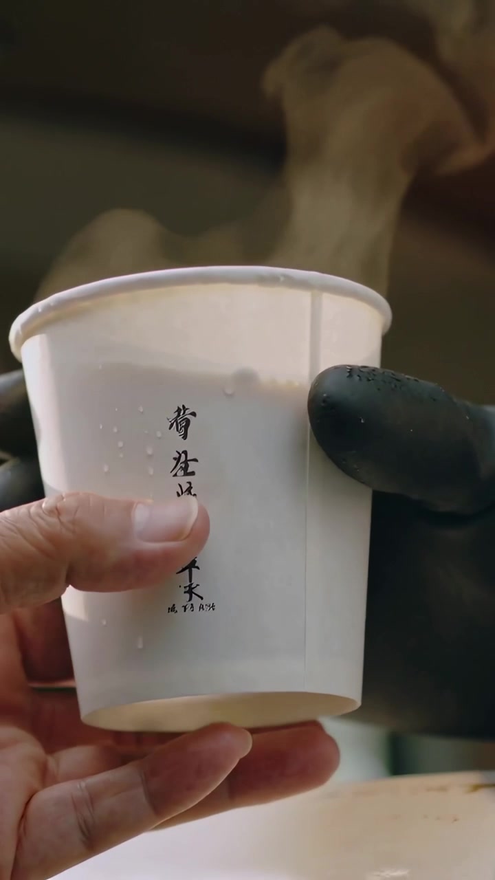 Video verticale: Consegna di una tazza calda stampata al bancone, un guanto che passa a una mano nuda che riceve la bevanda.