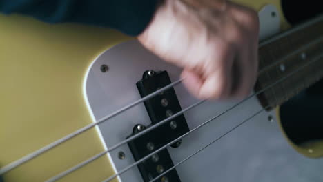 toca en solitario con las cuerdas de metal de la guitarra baja blanca