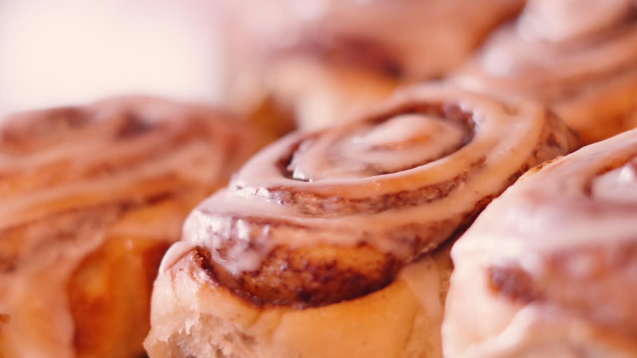 Freshly Baked Cinnamon Buns in Cafe Setting with Soft Natural Light. Sweet Bakery Treat with Icing Glaze