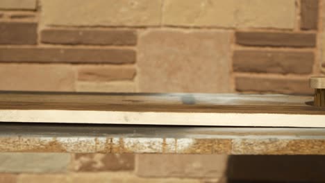 carpintero que aplica un cepillo de alambre en un tablón de madera de pino quemado, luego toca y siente la superficie, cierra