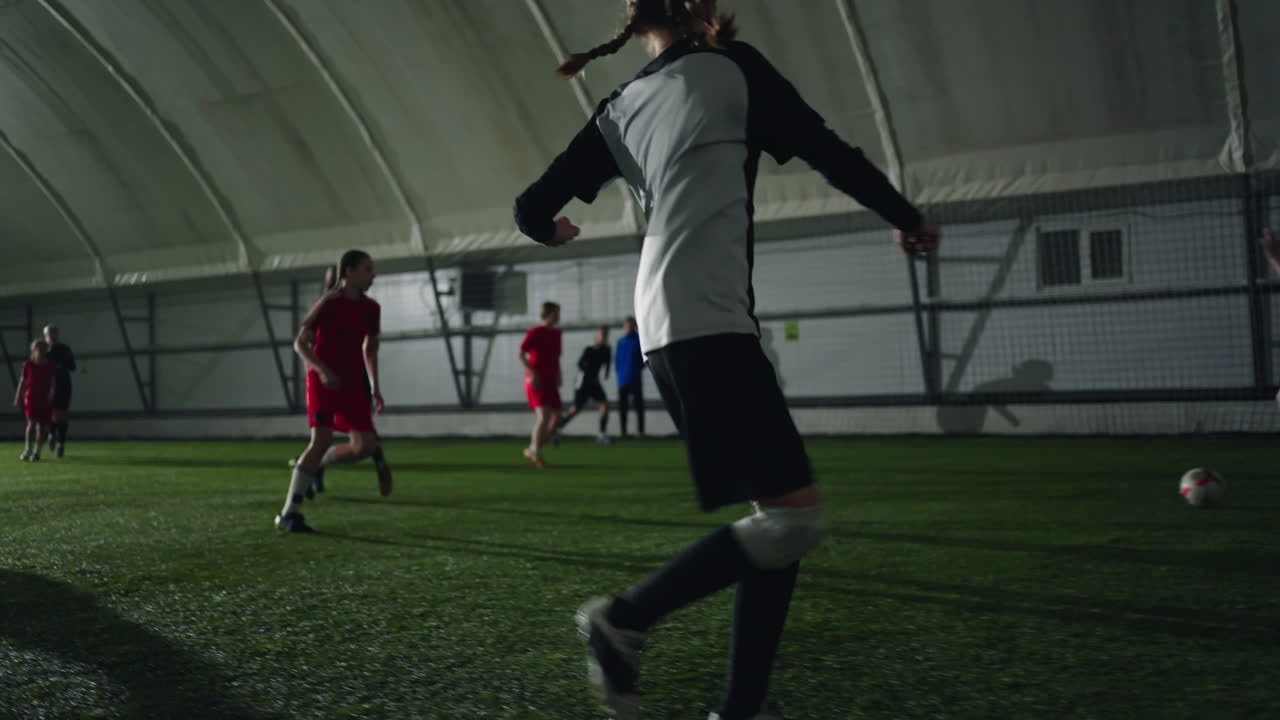 여자 운동 선수 들 이 경기장 에서 뛰고 있는 실내 축구 경기