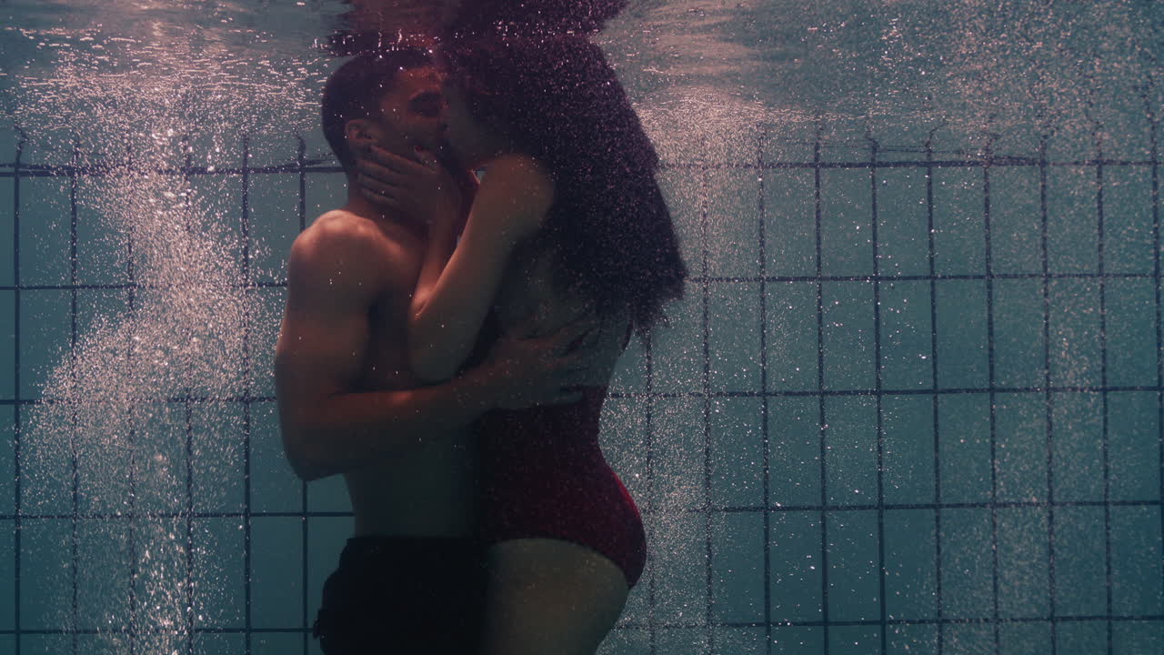 coppia sottomarina che si bacia in piscina giovani innamorati che si godono un bacio romantico amanti appassionati sommersi nell'acqua che galleggiano con bolle in intimità giocosa