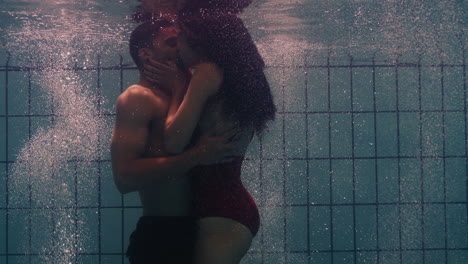 underwater couple kissing in swimming pool young people in love enjoying romantic kiss passionate lovers submerged in water floating with bubbles in playful intimacy