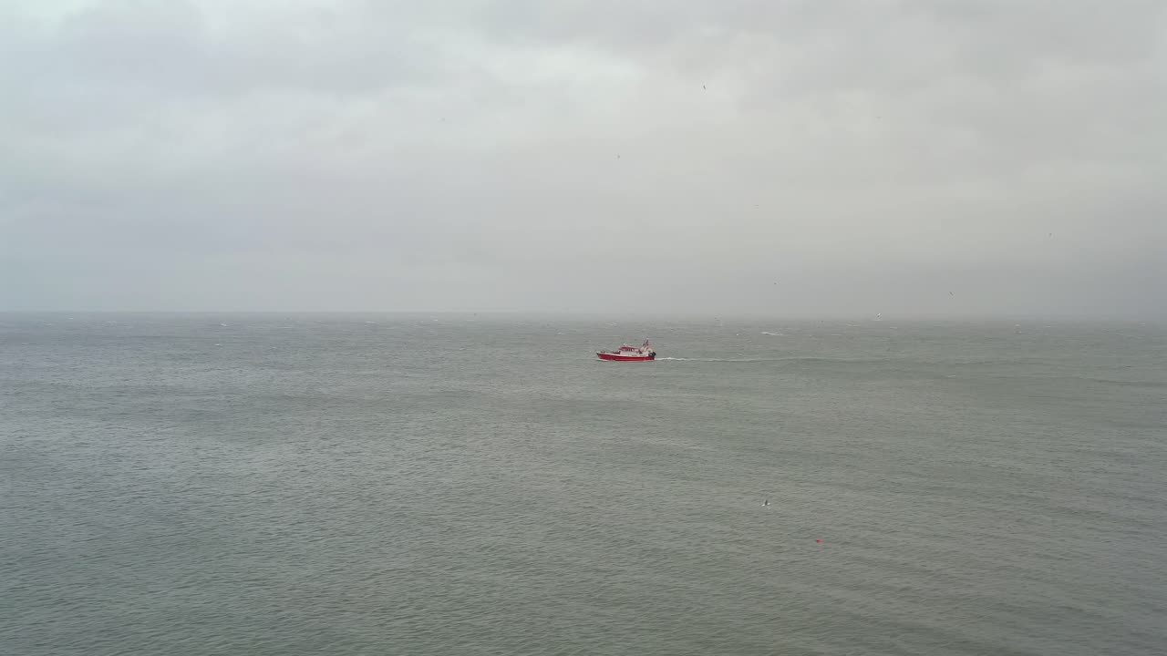 barco de pesca en la distancia en aguas abiertas del océano bajo un cielo nublado oscuro gris oscuro de irlanda