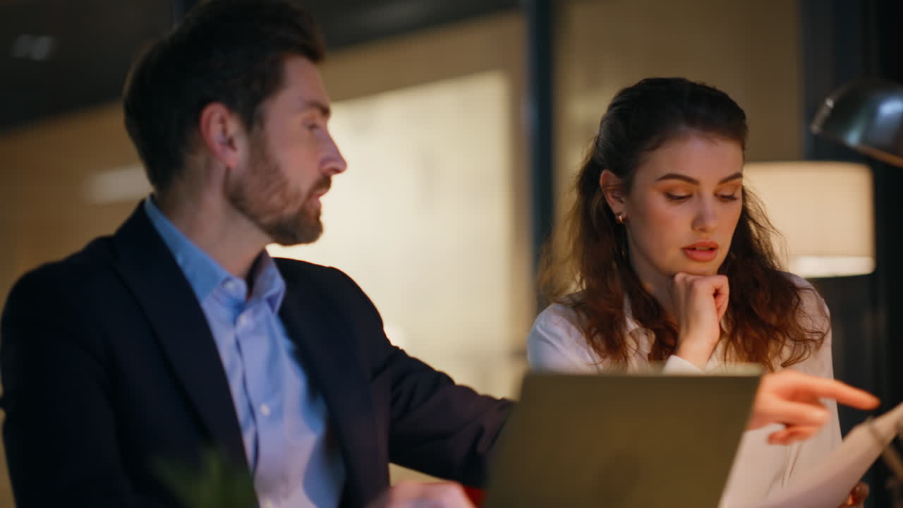 Businessman advising woman manager with paperwork sitting night office closeup