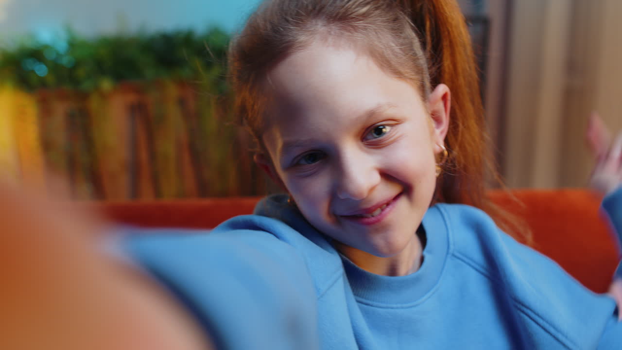 Child kid girl taking selfie on smartphone communicating video call home online with subscribers
