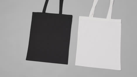 close up of white and black bags on grey background, with copy space, slow motion