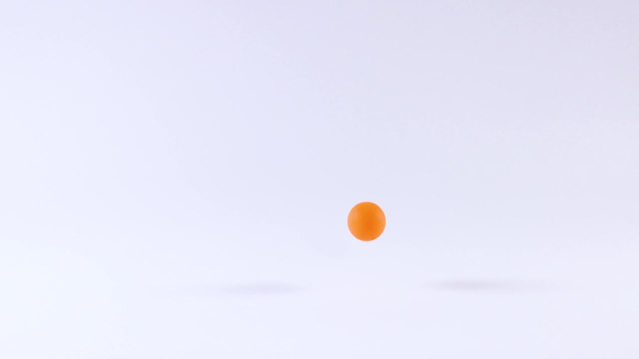 Oranssi pallo pomppii valkoisella pinnalla