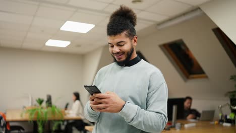 Exitoso-Hombre-De-Negocios-De-Raza-Mixta-Sonriendo-Mientras-Lee-El-Mensaje-En-El-Teléfono-Celular