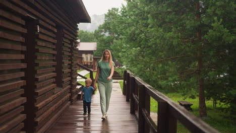 mother and little boy walk joining hands along veranda