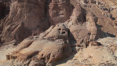 Una-Toma-Aérea-De-Un-Dron-De-Una-Extraña-Formación-Rocosa-Con-Forma-De-Cara-En-El-Desierto