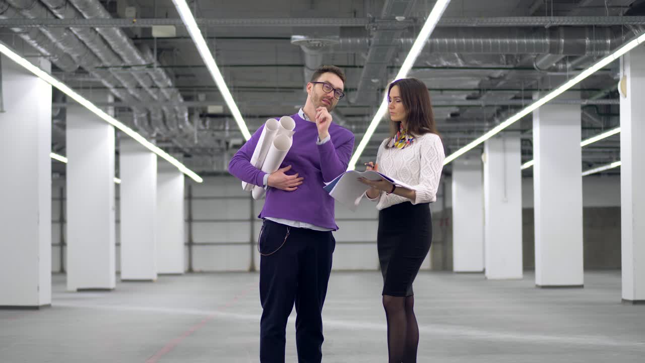 Arquitectos discuten un proyecto, sosteniendo planos en las manos.