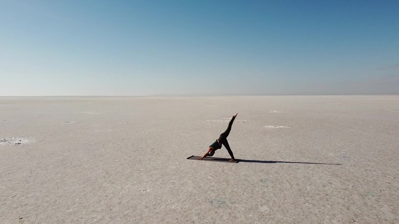 Bella ragazza bruna che pratica Yoga in un paesaggio selvaggio. Posizione del cane a testa in giù, meditazione sul Lago Tuz, Salar in Turchia. Buone vibrazioni, buona energia.