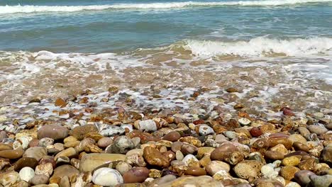 Close-up-blue-waves-breaking-over-a-colorful-rocky-shoreline-2