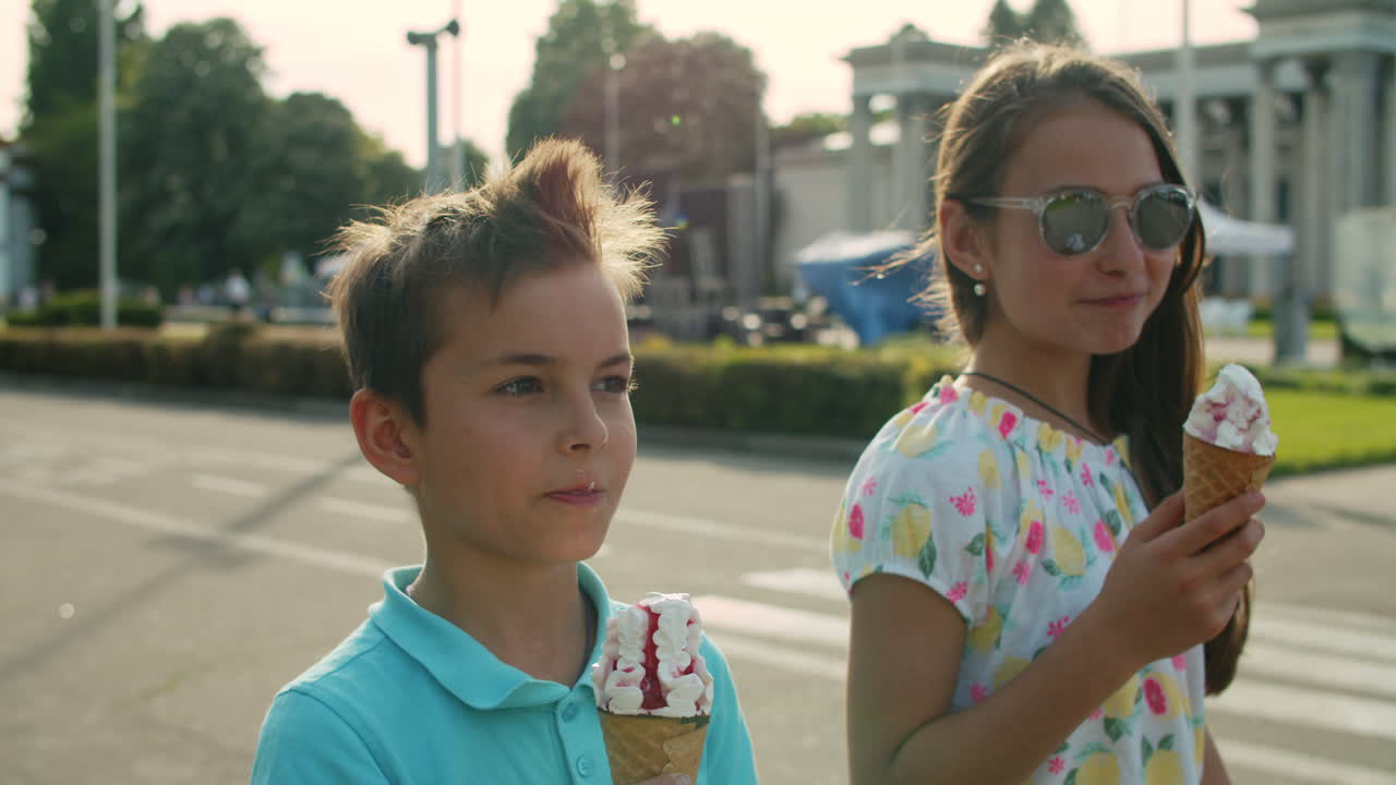 cute sister and brother eating ice cream. smiling kids walking in amusement  park