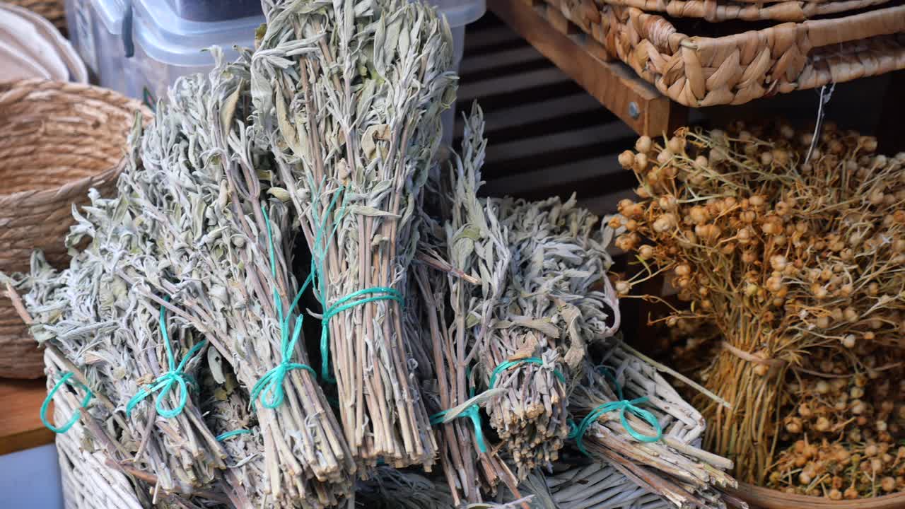 Mazzetti di erbe aromatiche essiccate e baccelli di semi esposti a un mercato